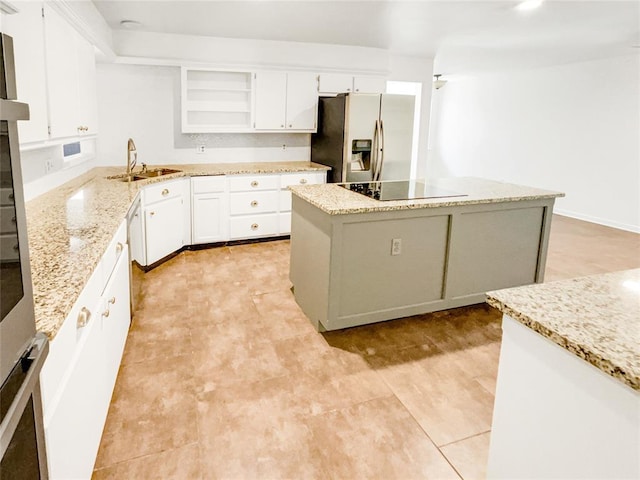 kitchen featuring stainless steel fridge, a sink, open shelves, a center island, and white cabinets