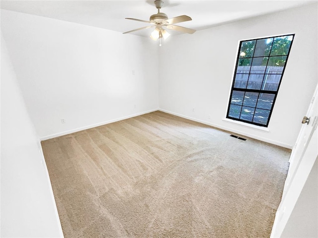 carpeted spare room featuring ceiling fan and baseboards