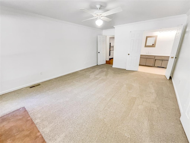 unfurnished bedroom featuring light colored carpet, crown molding, baseboards, and ensuite bathroom