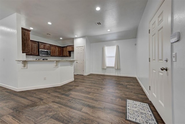 316 SW 4th Pl, Newcastle, OK 73065 - kitchen with stainless steel microwave, baseboards, a peninsula, dark wood finished floors, and light stone countertops