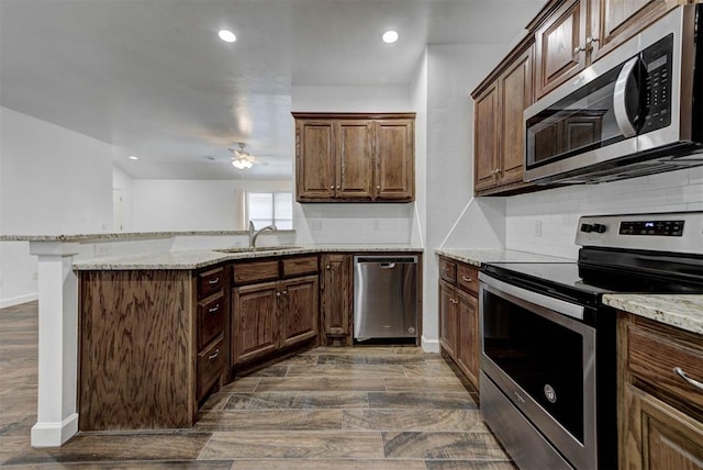 316 SW 4th Pl, Newcastle, OK 73065 - kitchen with stainless steel appliances, a peninsula, dark wood finished floors, decorative backsplash, and light stone counters