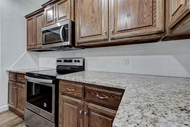 316 SW 4th Pl, Newcastle, OK 73065 - kitchen with appliances with stainless steel finishes, backsplash, baseboards, and wood finished floors