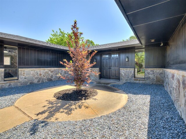 11008 Blue Sage Rd, Oklahoma City, OK 73120 - doorway to property featuring stone siding and board and batten siding