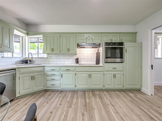 11008 Blue Sage Rd, Oklahoma City, OK 73120 - kitchen with appliances with stainless steel finishes, a sink, green cabinetry, light countertops, and backsplash