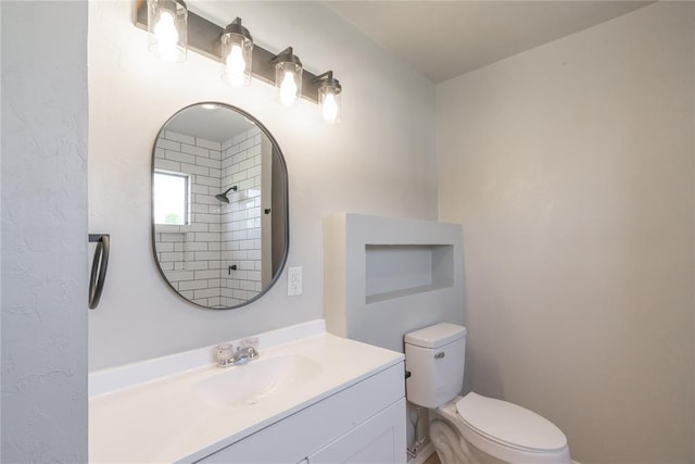 bathroom with toilet, vanity, and a shower