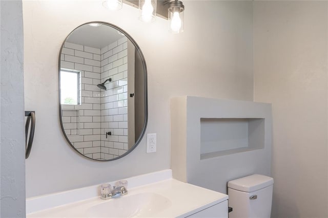 bathroom featuring toilet, vanity, and a shower