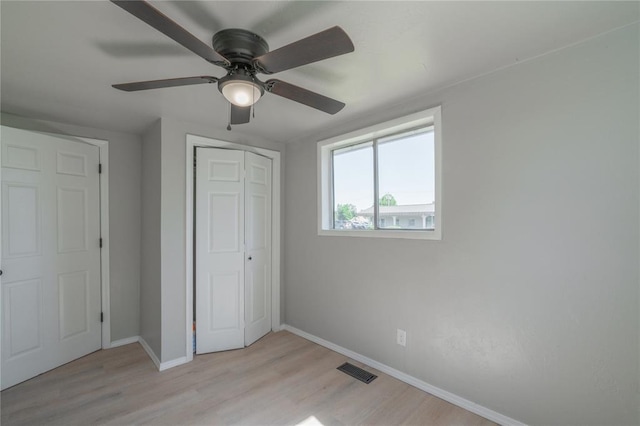 unfurnished bedroom with baseboards, light wood-type flooring, a closet, and a ceiling fan