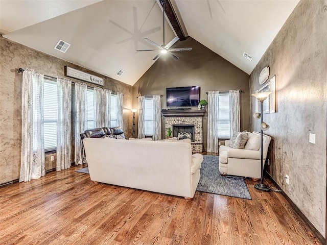 living room featuring a fireplace, ceiling fan, wood finished floors, beamed ceiling, and high vaulted ceiling