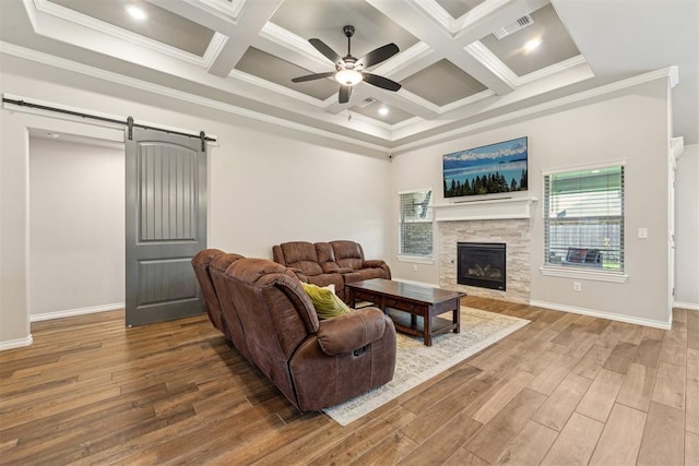living area featuring a ceiling fan, a barn door, wood finished floors, a fireplace, and coffered ceiling