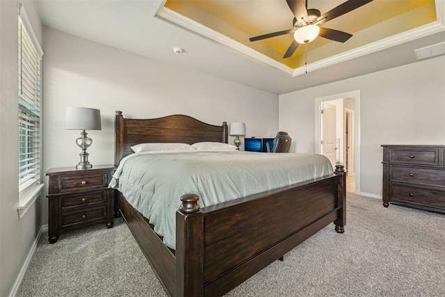 carpeted bedroom with a tray ceiling, baseboards, ceiling fan, and ensuite bath