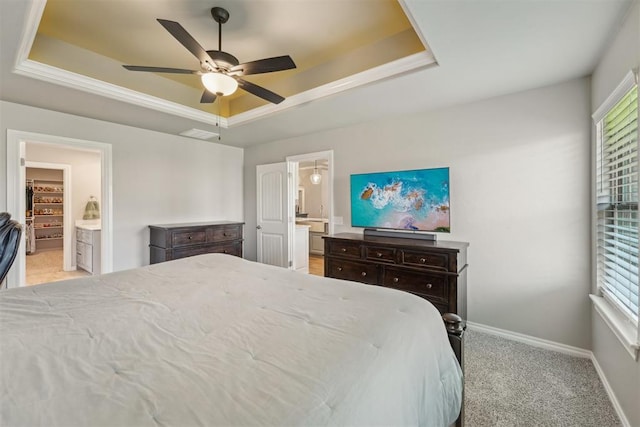 carpeted bedroom featuring a raised ceiling, multiple windows, and ensuite bathroom