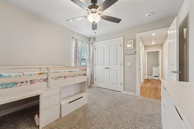 unfurnished bedroom featuring light colored carpet, a closet, a ceiling fan, and baseboards