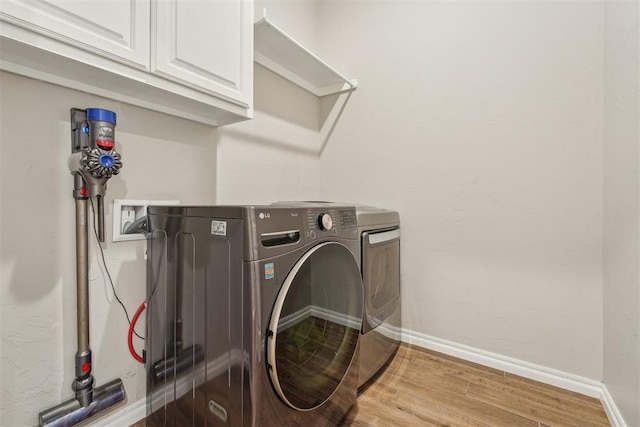 laundry room with cabinet space, wood finished floors, separate washer and dryer, and baseboards