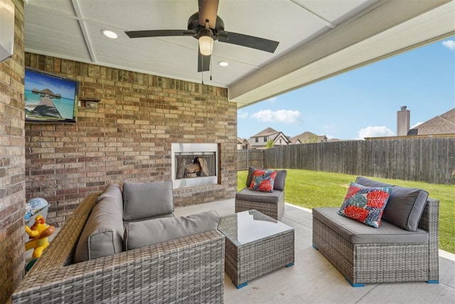 view of patio with an outdoor living space with a fireplace and a ceiling fan