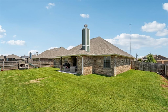 back of property with a playground, brick siding, a patio area, a chimney, and roof with shingles