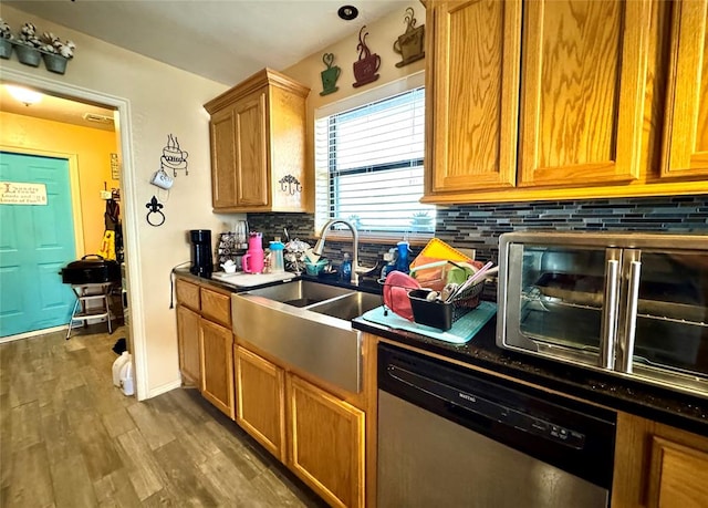 142 Skyline Dr, Chickasha, OK 73018 - kitchen with stainless steel dishwasher, dark countertops, backsplash, a sink, and wood finished floors