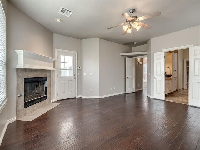 16104 Ledge Ln, Edmond, OK 73013 - unfurnished living room featuring ceiling fan, a tile fireplace, wood-type flooring, and baseboards