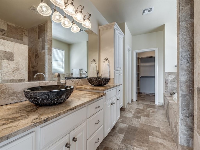 16104 Ledge Ln, Edmond, OK 73013 - bathroom with stone finish flooring, double vanity, a spacious closet, and a tub to relax in