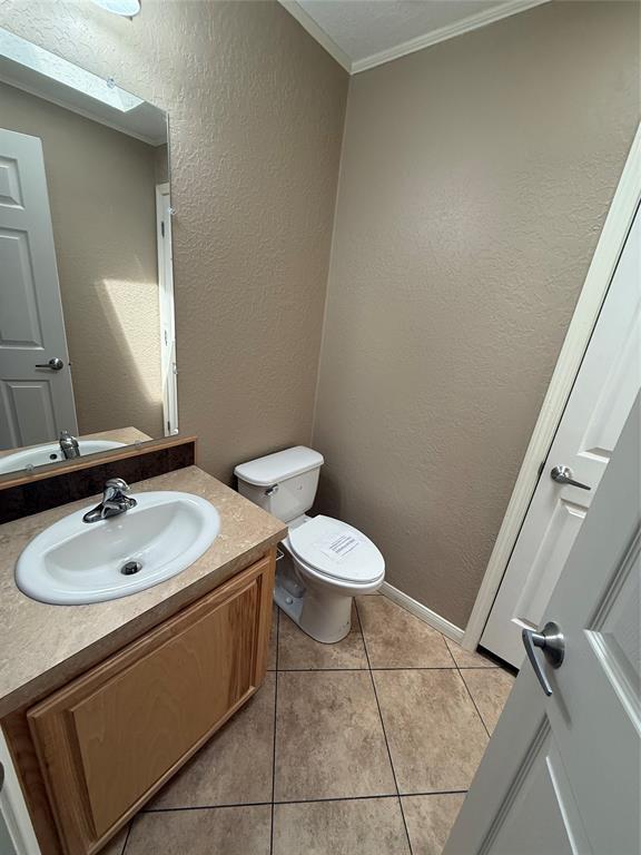 106 Sundown Ct, Mcloud, OK 74851 - half bath featuring toilet, vanity, ornamental molding, tile patterned flooring, and a textured wall
