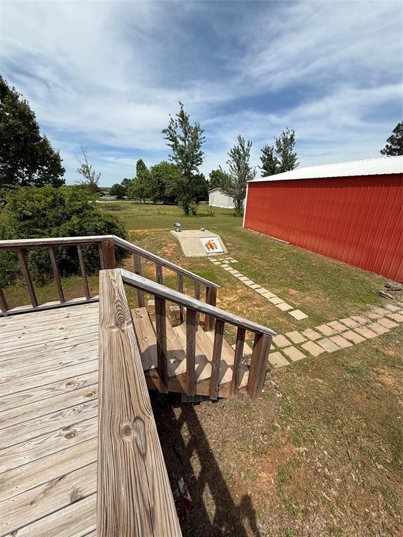 106 Sundown Ct, Mcloud, OK 74851 - wooden deck with a lawn, an outdoor structure, and an outbuilding