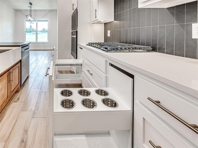 10424 SW 51st St, Mustang, OK 73064 - kitchen featuring appliances with stainless steel finishes, light wood finished floors, backsplash, and white cabinetry