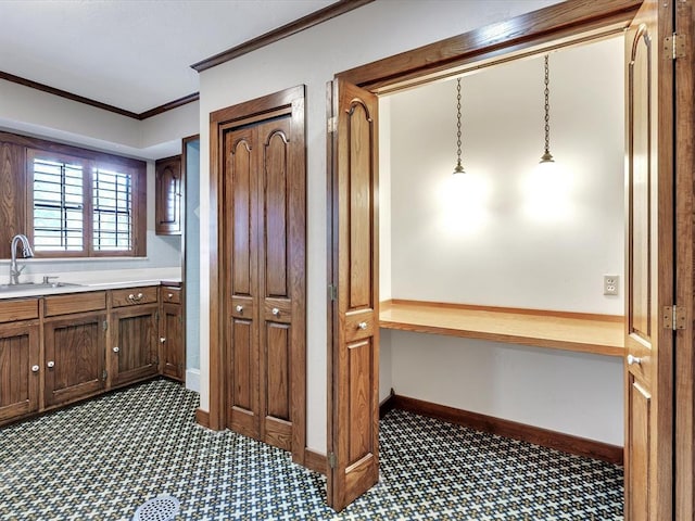 100 Maple Ln, Chickasha, OK 73018 - kitchen featuring a sink, dark carpet, crown molding, light countertops, and baseboards