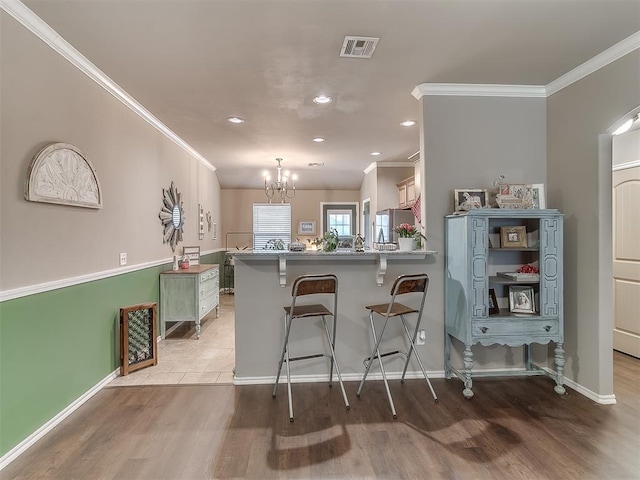 2536 Canyon Creek Dr, Yukon, OK 73099 - kitchen with crown molding, a chandelier, a kitchen breakfast bar, light wood-type flooring, and recessed lighting