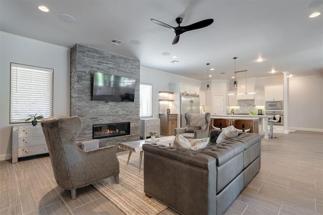 3419 Abby Ln, Newcastle, OK 73065 - living room featuring a ceiling fan, ornamental molding, a stone fireplace, baseboards, and recessed lighting