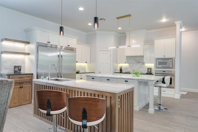 3419 Abby Ln, Newcastle, OK 73065 - kitchen with built in appliances, a kitchen island with sink, a sink, tasteful backsplash, and a breakfast bar area