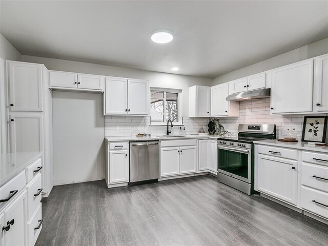 3325 NW 65th St, Oklahoma City, OK 73116 - kitchen with appliances with stainless steel finishes, under cabinet range hood, wood finished floors, white cabinetry, and recessed lighting