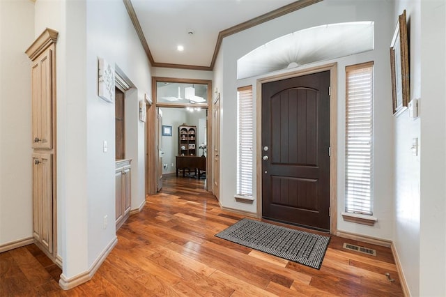 foyer with ornamental molding, light wood-style flooring, and baseboards