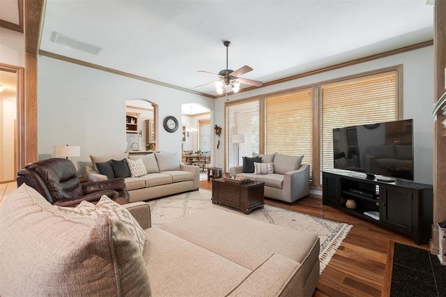 living area with crown molding, arched walkways, a ceiling fan, and wood finished floors