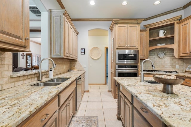 kitchen featuring stainless steel appliances, a sink, crown molding, decorative backsplash, and light stone countertops