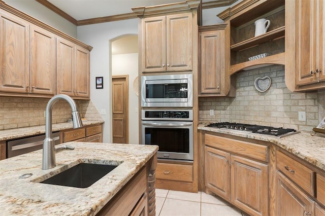 kitchen with appliances with stainless steel finishes, a sink, tasteful backsplash, light stone counters, and light tile patterned floors