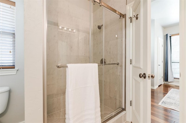 bathroom featuring a stall shower, toilet, and wood finished floors