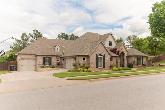 french country style house featuring brick siding, an attached garage, fence, and concrete driveway