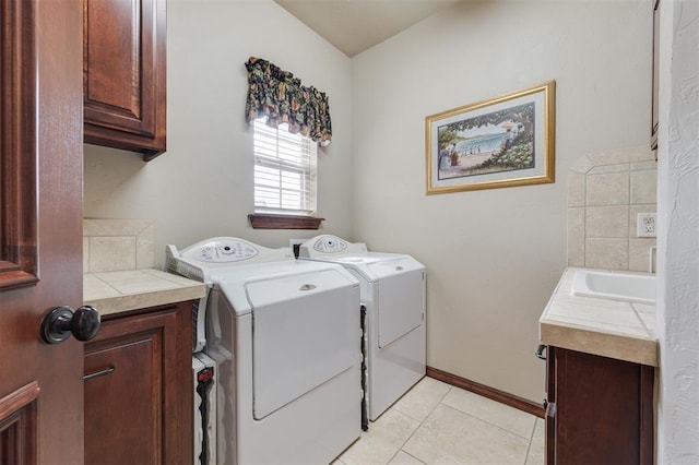clothes washing area featuring cabinet space, washer and dryer, light tile patterned floors, and baseboards