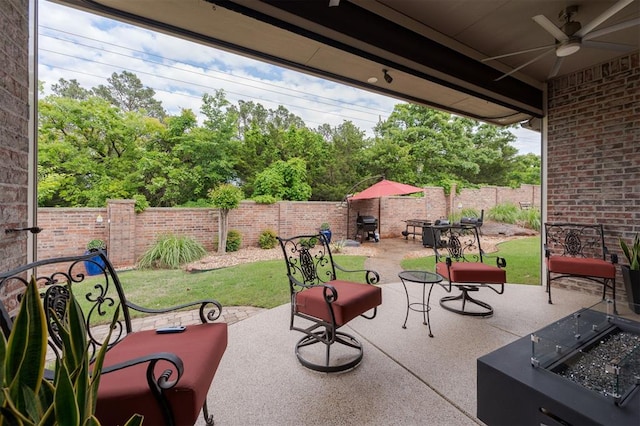 view of patio featuring a fenced backyard, a ceiling fan, an outdoor fire pit, and a grill
