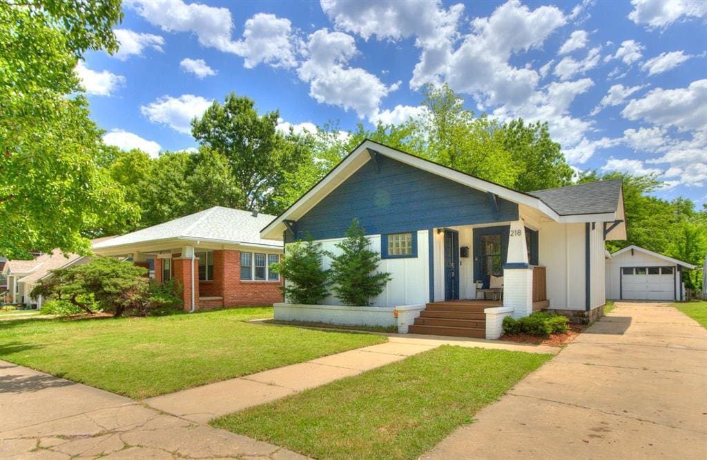 218 E Duffy St, Norman, OK 73069 - view of front of house with driveway, a porch, an outbuilding, a front yard, and a garage
