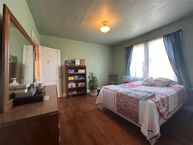 bedroom with dark wood-type flooring and baseboards
