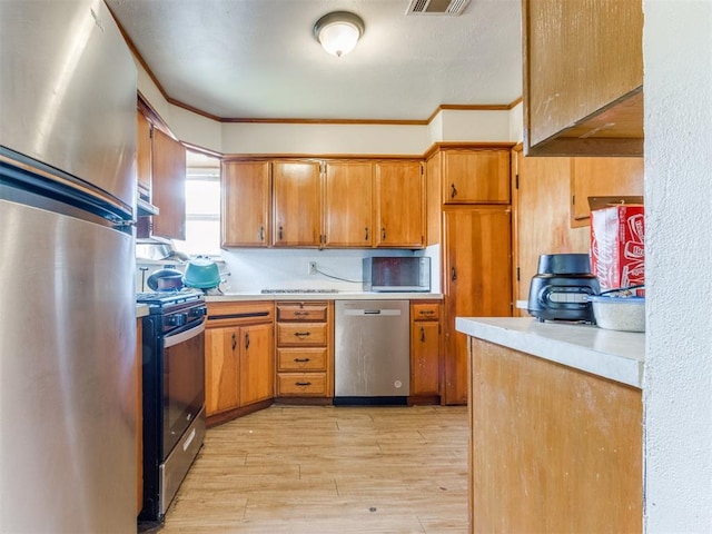2210 SW 52nd St, Oklahoma City, OK 73119 - kitchen with stainless steel appliances, light wood-style flooring, light countertops, brown cabinets, and ornamental molding