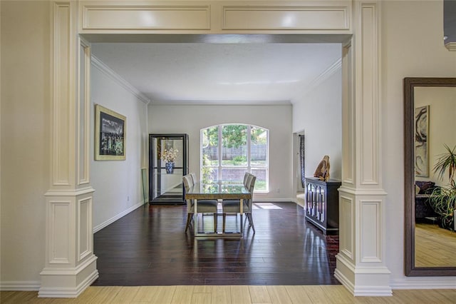 dining space featuring ornate columns, ornamental molding, wood finished floors, and baseboards