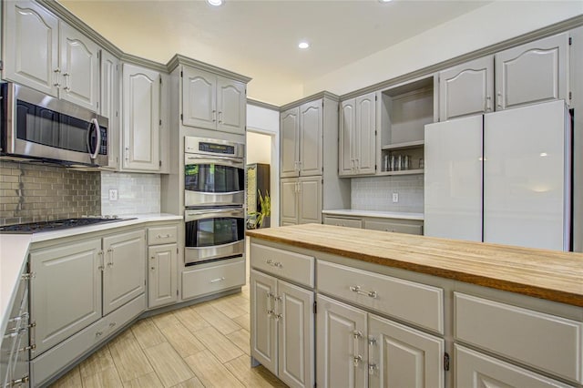 kitchen with appliances with stainless steel finishes, gray cabinetry, backsplash, open shelves, and recessed lighting