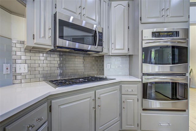 kitchen with appliances with stainless steel finishes, light countertops, and decorative backsplash