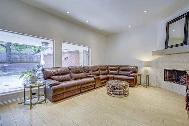 living room with a stone fireplace, recessed lighting, and light wood-style flooring