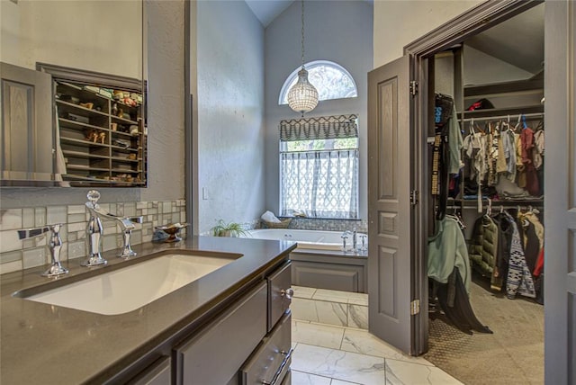 full bathroom featuring a spacious closet, a bath, marble finish floors, vanity, and high vaulted ceiling
