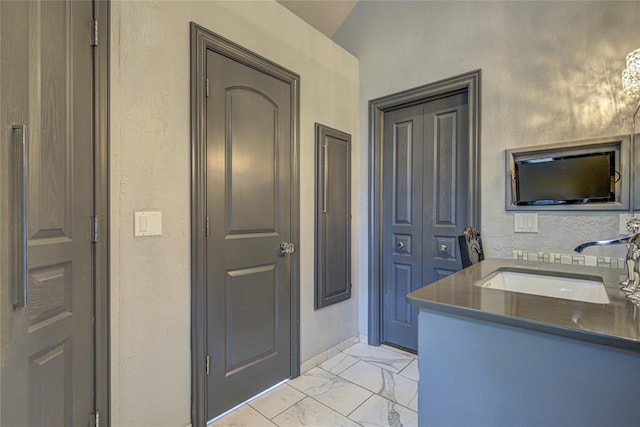 bathroom featuring a textured wall, marble look tiles, and vanity