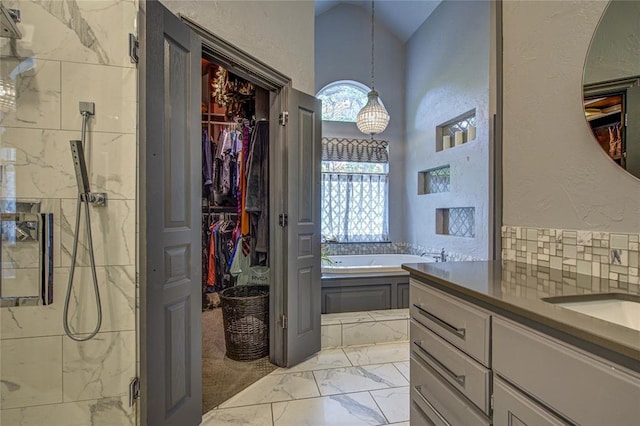 bathroom with a marble finish shower, marble look tile flooring, a spacious closet, a bath, and high vaulted ceiling
