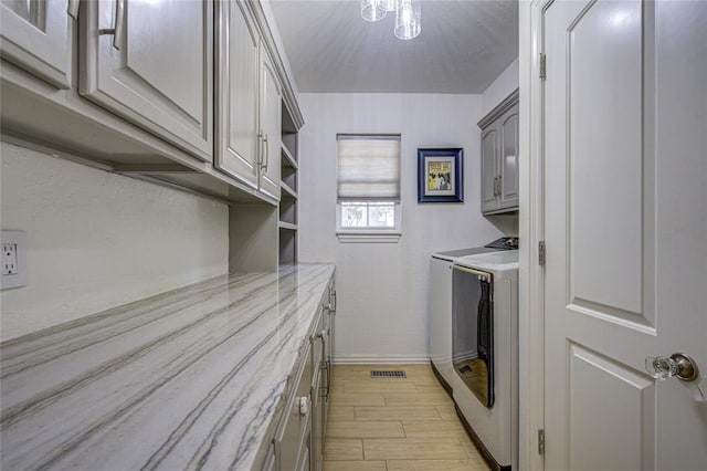 laundry room featuring separate washer and dryer, cabinet space, light wood-type flooring, and baseboards