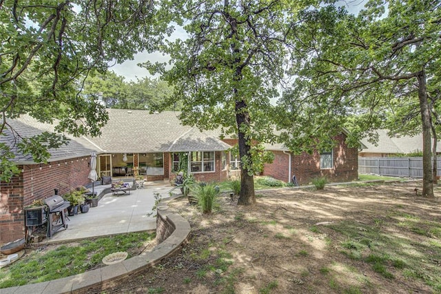 back of property featuring a patio, brick siding, fence, and roof with shingles